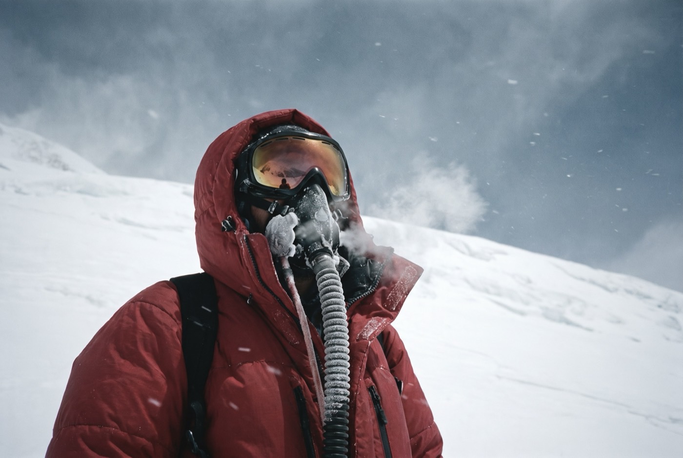 A climber on oxygen high on Cho Oyu, frost on the regulator hose and the snow slope reflected in their goggles