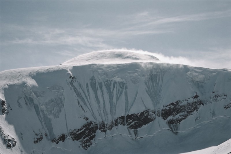 The broad summit dome of Cho Oyu with spindrift streaming off the crest, empty of people